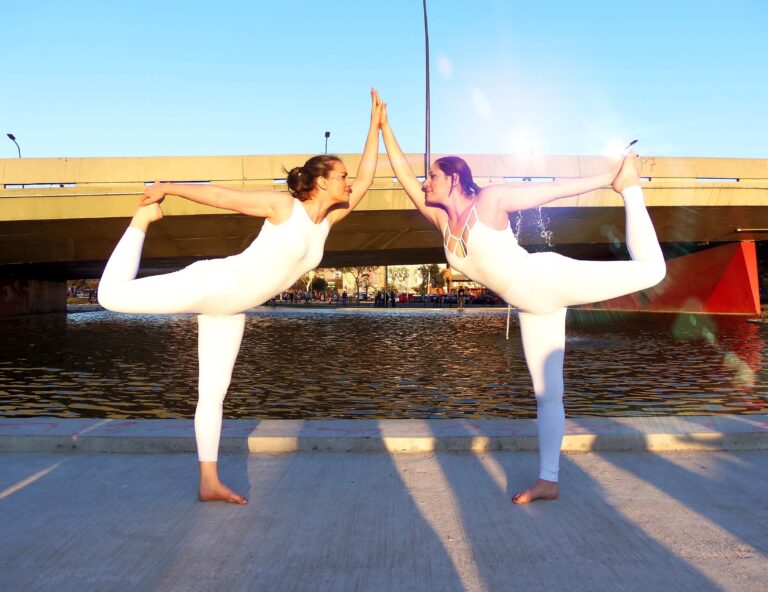 duas garotas unidas pelas mão no natarajasana acroyoga